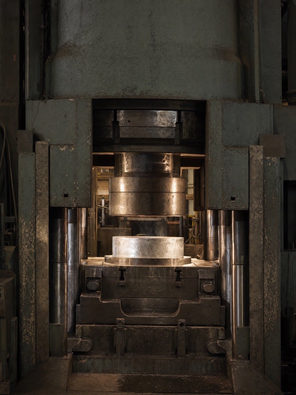 A forging press compressing an aluminum blank between steel dies